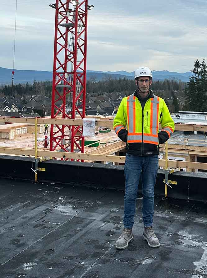 Chad Currie with CCOHS Group staind in front of tall crane on rooftop